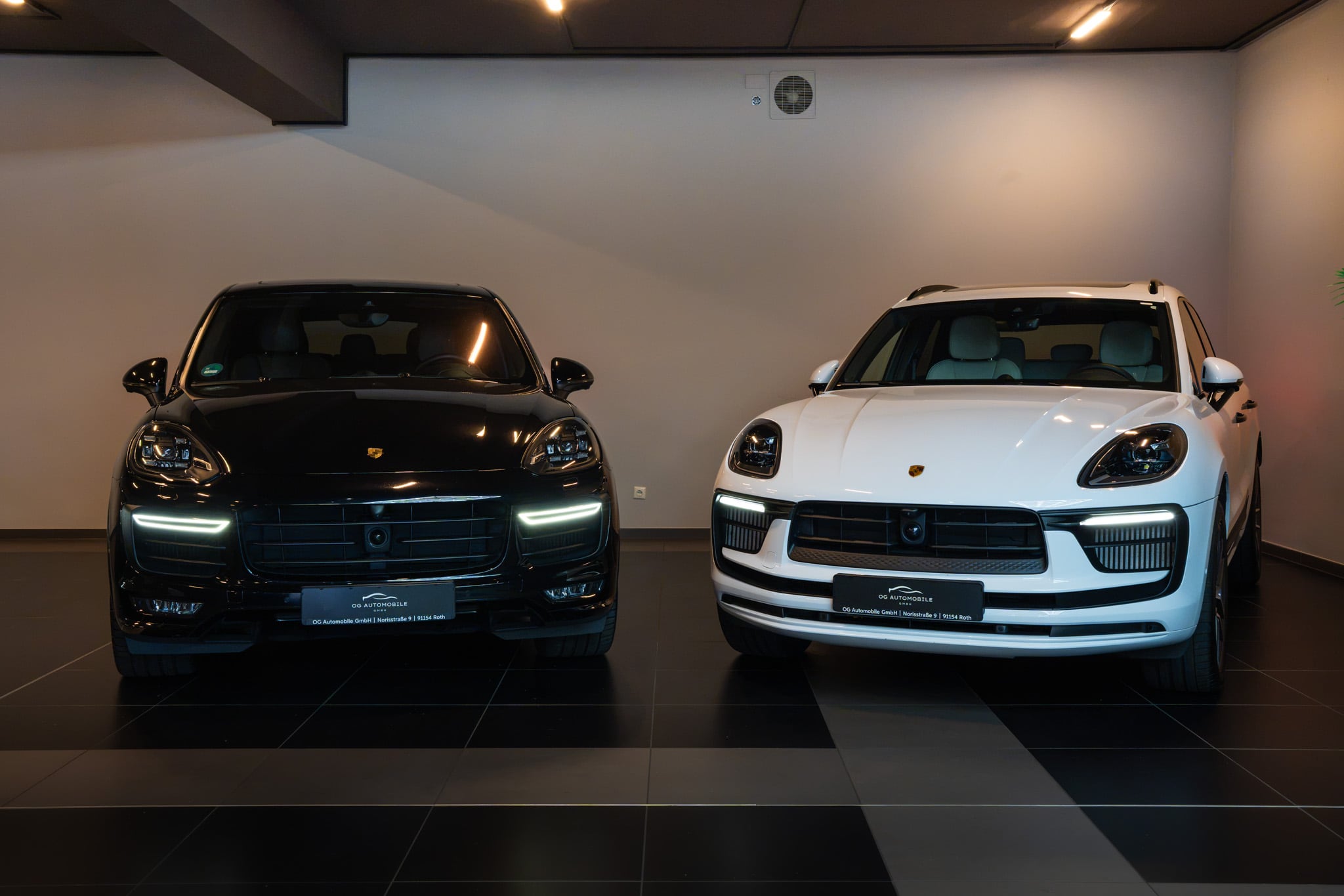 Zwei Porsche-SUVs in Schwarz und Weiß im Showroom in Roth